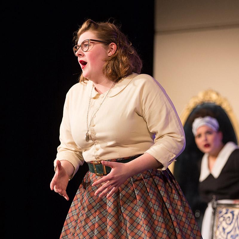 A Drake University student in costume performing on the theater stage